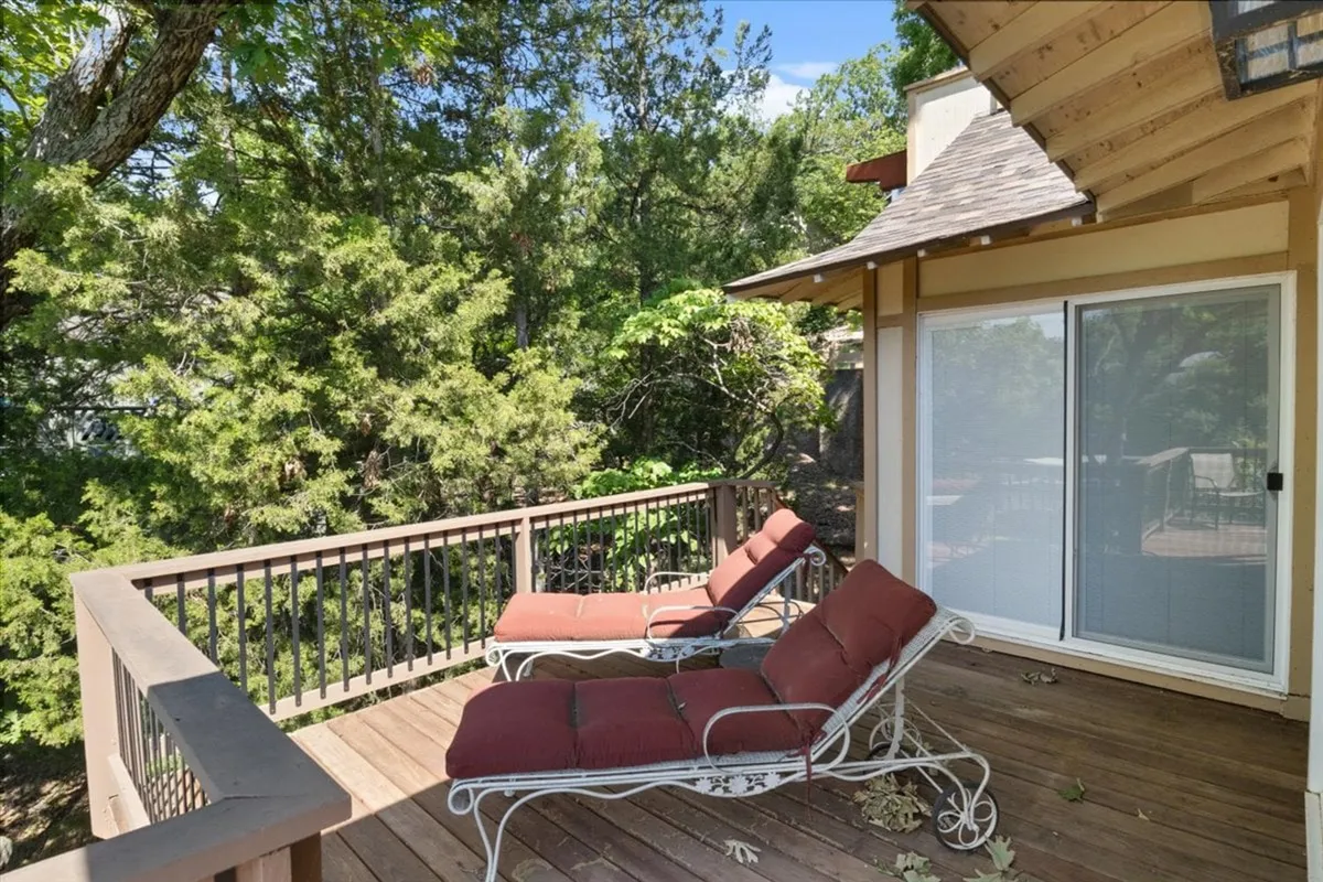 This image features a wooden deck with red lounge chairs, surrounded by lush greenery. The atmosphere is tranquil, inviting guests to relax, sunbathe, or enjoy a morning coffee outdoors while taking in the serene natural setting.