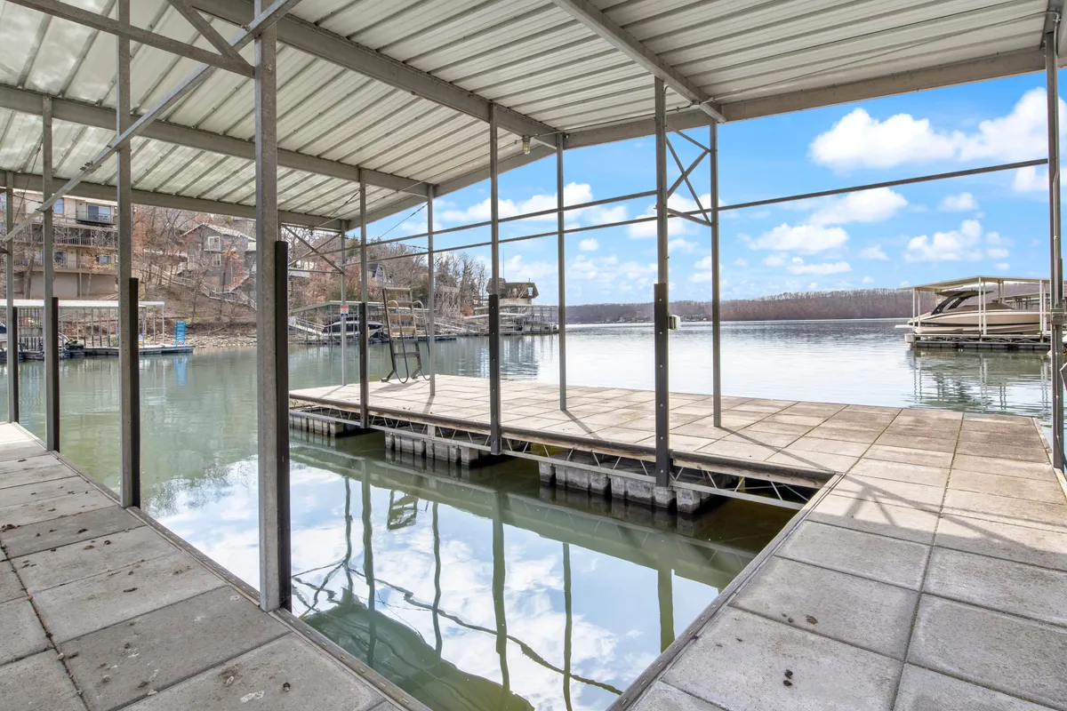 This image captures a tranquil dock extending over calm lake waters with beautiful natural surroundings. The setting is peaceful and inviting, perfect for early morning paddles, fishing, or gathering friends for lakeside relaxation.