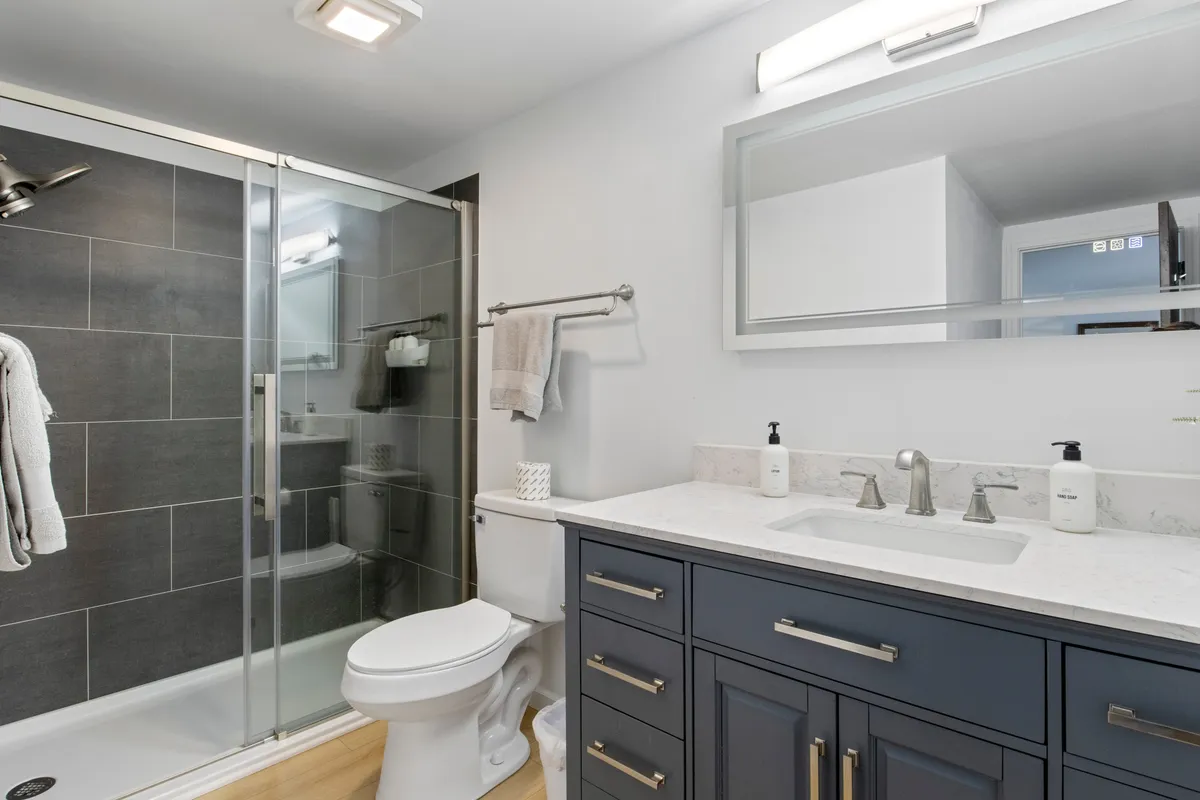 A modern bathroom featuring a glass shower enclosure, vanity with a marble countertop, and sleek, updated hardware. The space is bright, inviting, and spa-like, with an overall clean and refreshing feel.