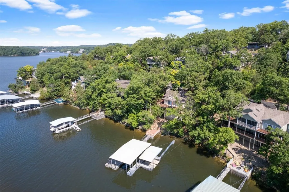 A picturesque shot of the lake with inviting docks, surrounding greenery, and neighboring houses in the background. The scene feels serene but also lively, offering a glimpse of the broader lakeside community.