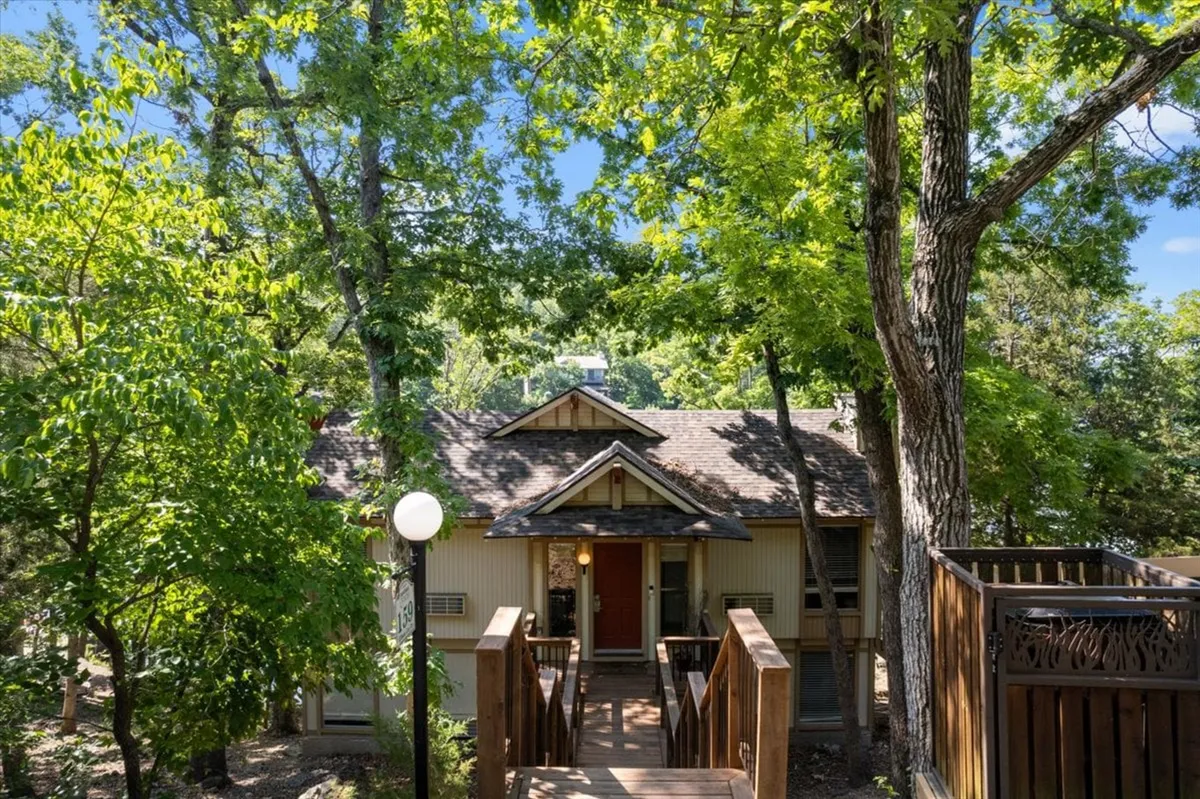The welcoming front entrance of the house, set amongst tall trees with a wooden walkway leading up. The atmosphere feels inviting and peaceful—suggesting a gateway to family adventures and shared experiences both inside and out.