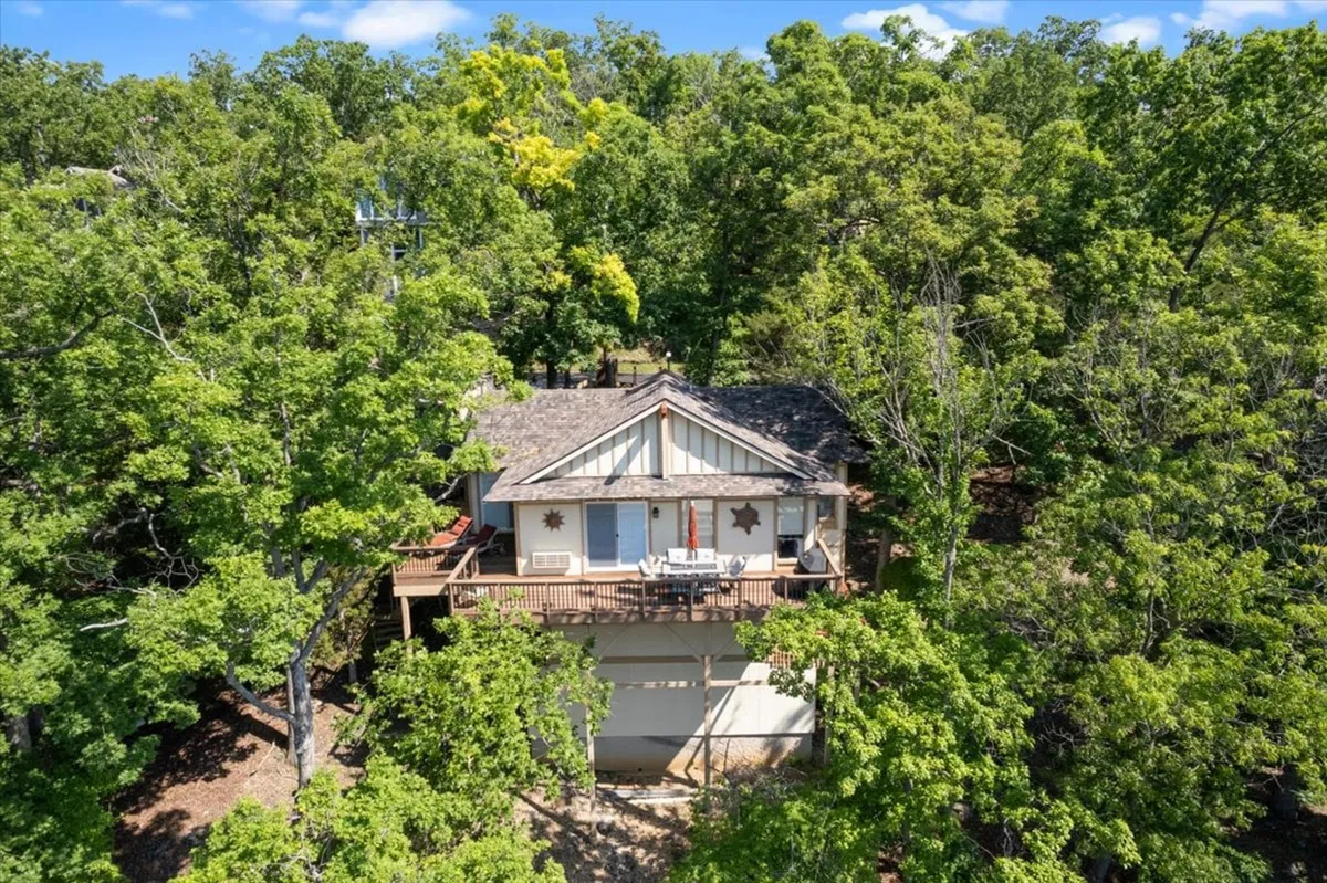 A wide-angle view of the house’s expansive wooden deck surrounded by lush trees, the deck is furnished and ideal for outdoor gatherings, barbecues, or lounging together in nature.