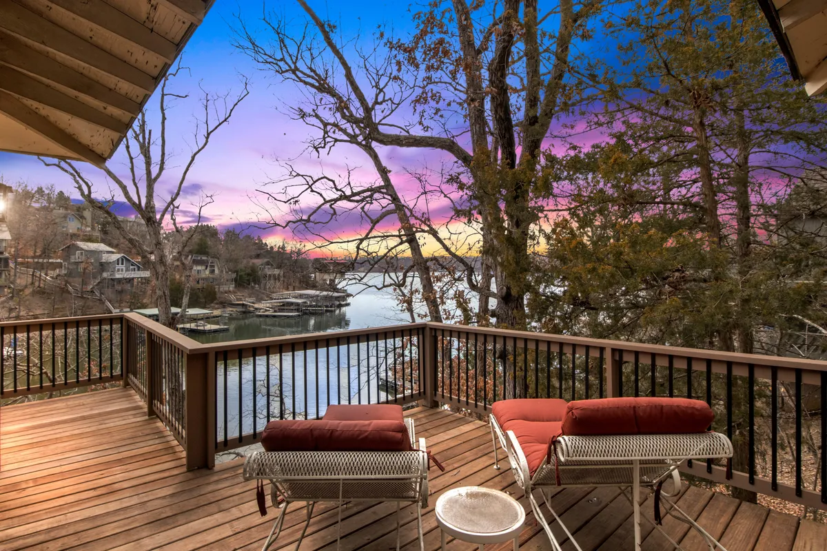 A spacious wooden deck overlooking a serene lake, outfitted with comfortable outdoor seating. The setting is ideal for relaxing, socializing, and enjoying sunsets or stargazing, encouraging group gatherings and outdoor meals.